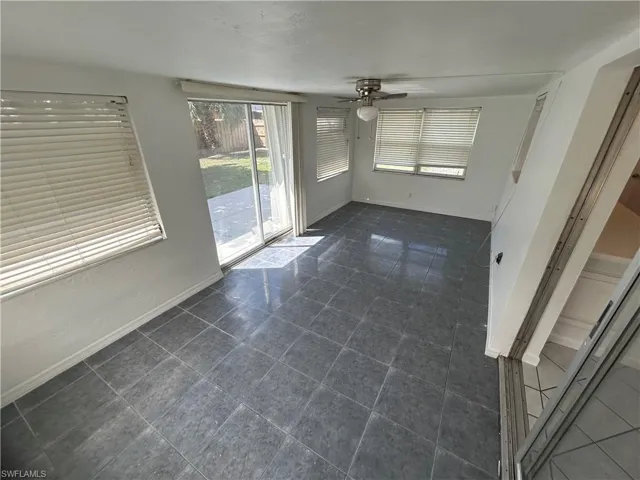 Unfurnished room featuring dark tile patterned floors and ceiling fan