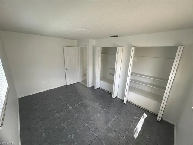 Unfurnished bedroom featuring a textured ceiling and dark tile patterned flooring