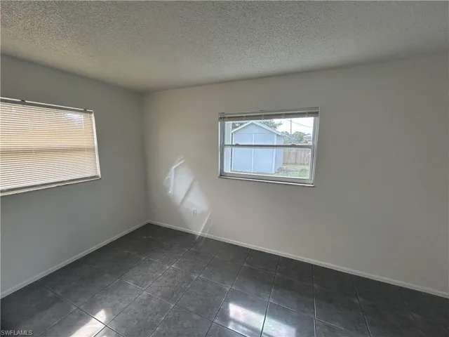 Unfurnished room with dark tile patterned flooring and a textured ceiling