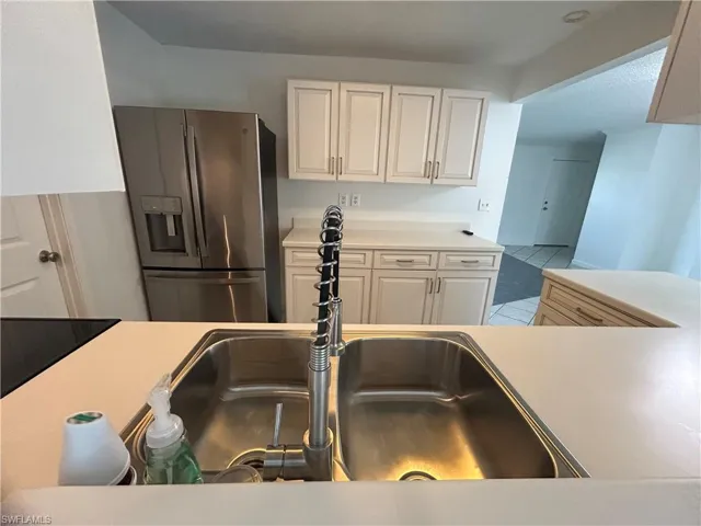 Kitchen with white cabinets, sink, and stainless steel refrigerator with ice dispenser