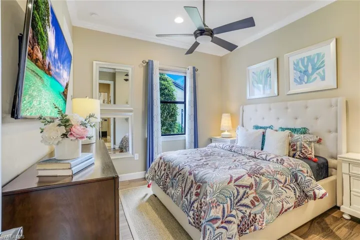 Guest Bedroom with walk-in custom closet. Ceiling crown molding, wood-like plank tile flooring, and ceiling fan