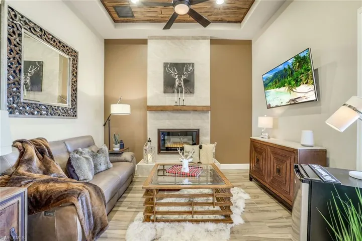 Den with a tongue and groove ceiling, large wood-like plank tiles, and a decorative fireplace and hearth