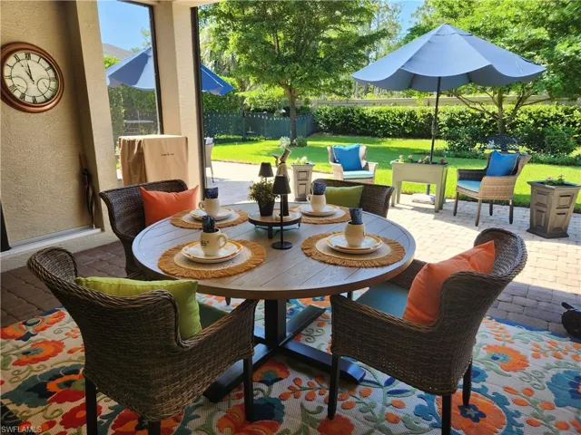 View of covered lanai with retractable screen patio / terrace.  Overlooking extended paver patio and large fenced in private backyard with mature shade trees.