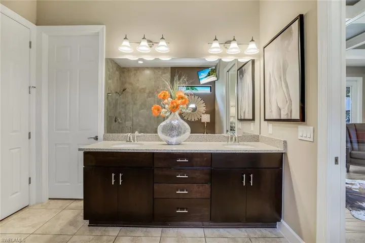 Owner's Bathroom featuring tile floors, large frameless shower and double sink vanity