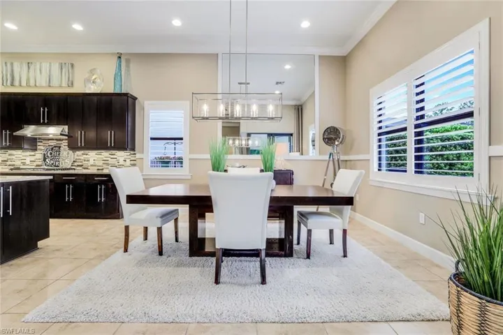 Tiled dining area featuring a wealth of natural light, ornamental molding and custom mirror