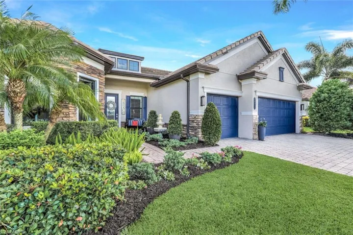 View of front of home with an oversized three car garage and a lushly, upgraded landscaped front yard.