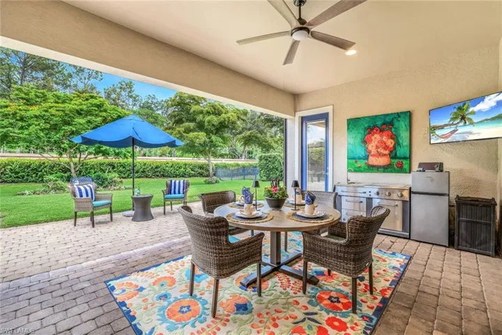View of covered and screened retractable screen lanai with ceiling fan and outdoor portable kitchen