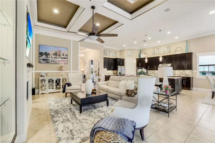 Great room with coffered ceiling, a decorative fireplace, large, custom built-in wall, ceiling fan, crown molding, and  tile floors