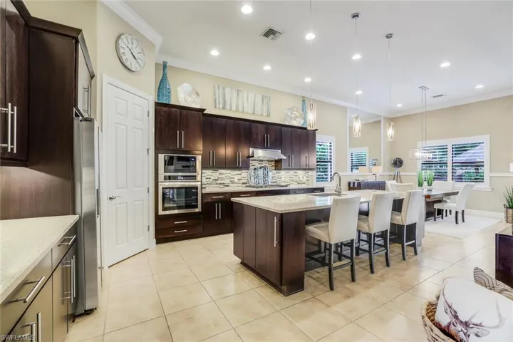 Gourmet, upgraded, natural gas Kitchen with walk-in pantry, tasteful backsplash, pendant lighting, solid surface counters, a 10' kitchen island with sink, and appliances with stainless steel finishes