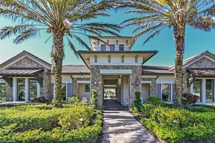 View of front of clubhouse featuring fitness center, clubhouse community room with kitchen, tropical setting with pool, firepit area, grilling area, bocce ball and more.  Community gatherings too!