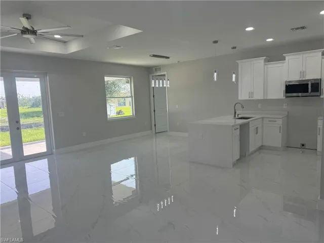 Kitchen featuring white cabinetry, light tile patterned floors, ceiling fan, decorative light fixtures, and sink