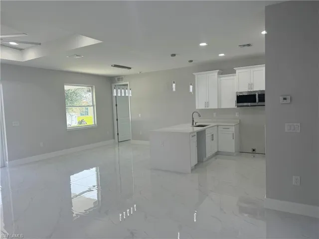 Kitchen with hanging light fixtures, sink, light tile patterned floors, and kitchen peninsula
