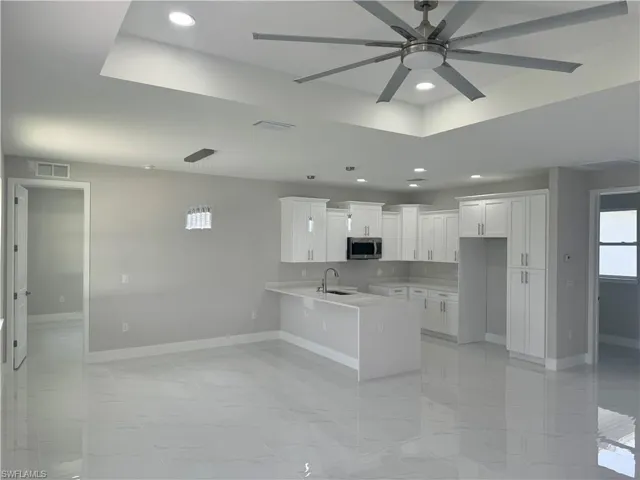 Kitchen with white cabinets, sink, kitchen peninsula, decorative light fixtures, and light tile patterned floors