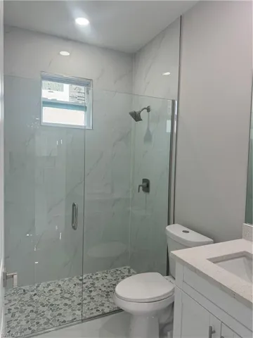 Bathroom with vanity, an enclosed shower, and toilet