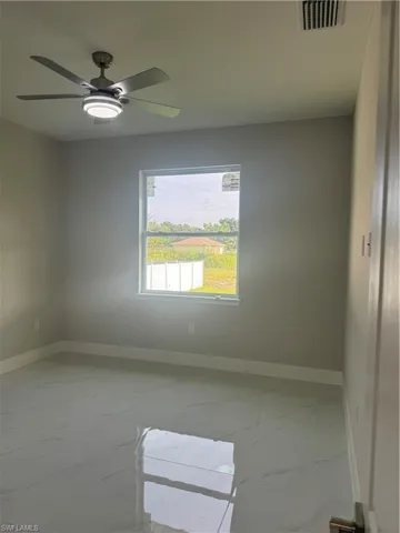 Spare room with ceiling fan and light tile patterned floors