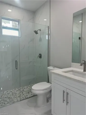 Bathroom with tile patterned flooring, a shower with door, toilet, and vanity