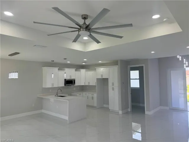 Kitchen featuring white cabinetry, ceiling fan, kitchen peninsula, sink, and light tile patterned floors