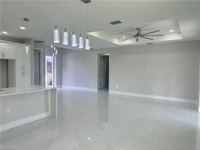 Spare room featuring ceiling fan, a raised ceiling, and light tile patterned floors