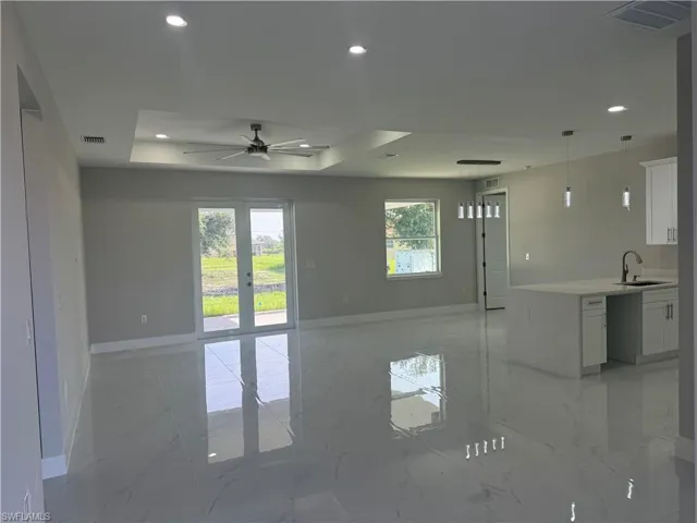 Tiled spare room with sink, ceiling fan, and a raised ceiling