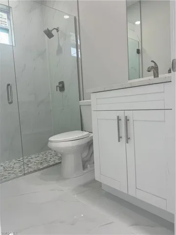 Bathroom featuring vanity, an enclosed shower, tile patterned flooring, and toilet