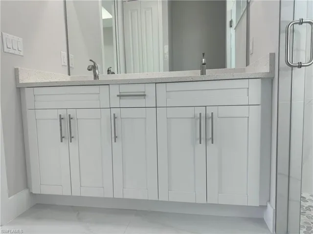 Bathroom featuring a shower with shower door, tile patterned floors, and vanity
