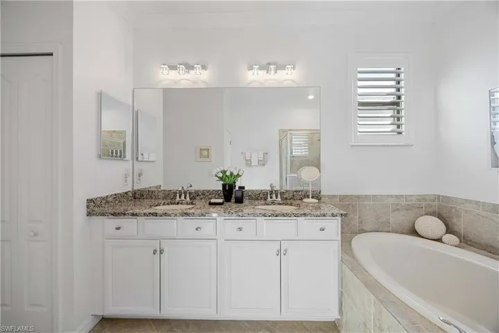 Full bathroom with double vanity, a bath, a shower stall, ornamental molding, and a closet