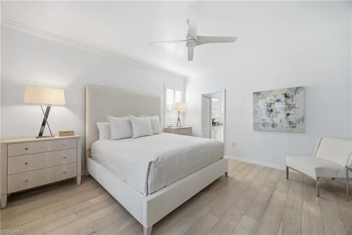 Bedroom featuring ornamental molding, light wood finished floors, ceiling fan, and ensuite bathroom