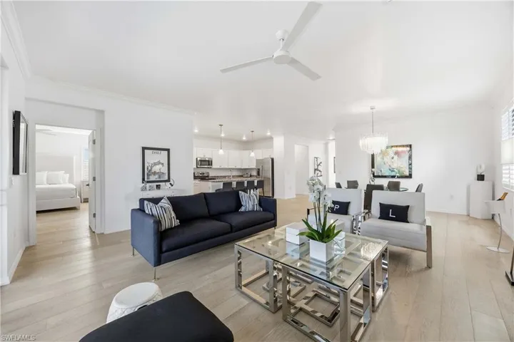 Living area with crown molding, light wood finished floors, ceiling fan, and hanging lights