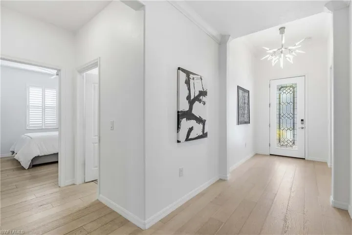 Entryway featuring light wood-style floors, crown molding, and suspended lighting