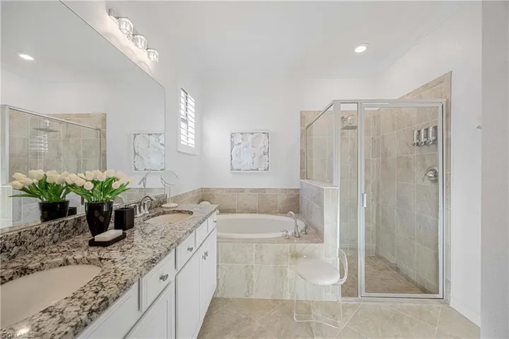 Full bathroom with a garden tub, a shower stall, double vanity, ornamental molding, and recessed lighting