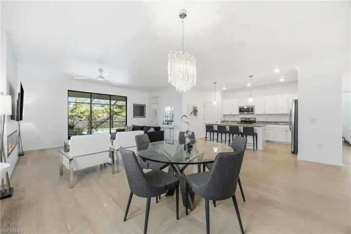 Dining area with ornamental molding, light wood-type flooring, ceiling fan, and a chandelier