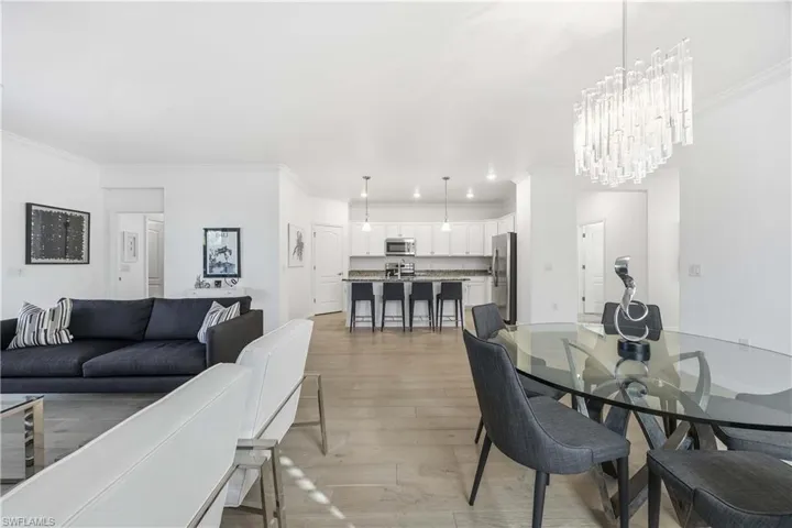 Dining space with light wood finished floors, ornamental molding, and hanging lights