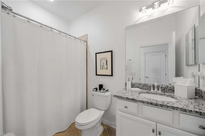 Full bathroom featuring vanity, a shower with shower curtain, and dark tile patterned flooring