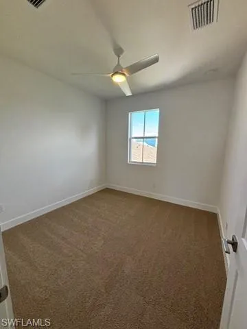 Empty room featuring ceiling fan and carpet