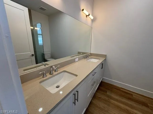 Bathroom with hardwood / wood-style floors, toilet, and vanity
