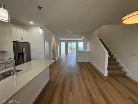 Kitchen with stainless steel fridge with ice dispenser, hardwood / wood-style flooring, hanging light fixtures, and sink