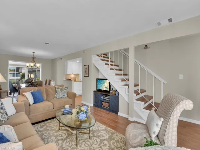 Living room with stairway, light wood-style floors, a chandelier, and baseboards