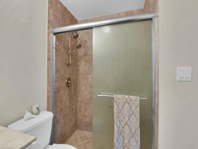 Full bath featuring a stall shower, toilet, and vanity