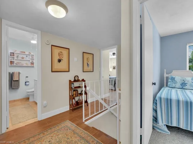 Hallway with an upstairs landing, wood finished floors, and baseboards