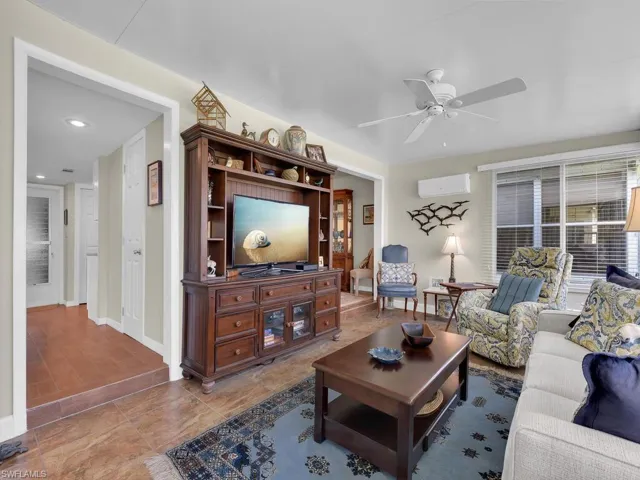 Living area featuring an AC wall unit, a ceiling fan, baseboards, and recessed lighting