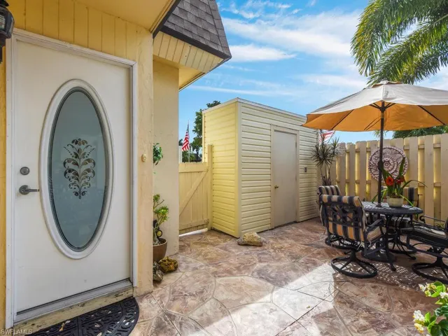 Doorway to property featuring a patio area, outdoor dining space, roof with shingles, and stucco siding