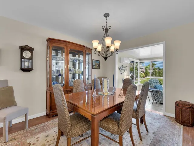 Dining area featuring a chandelier, light wood-style flooring, baseboards, and an AC wall unit