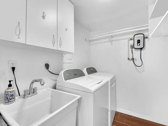 Laundry room with cabinet space, wood finish floors, washer and clothes dryer, and baseboards