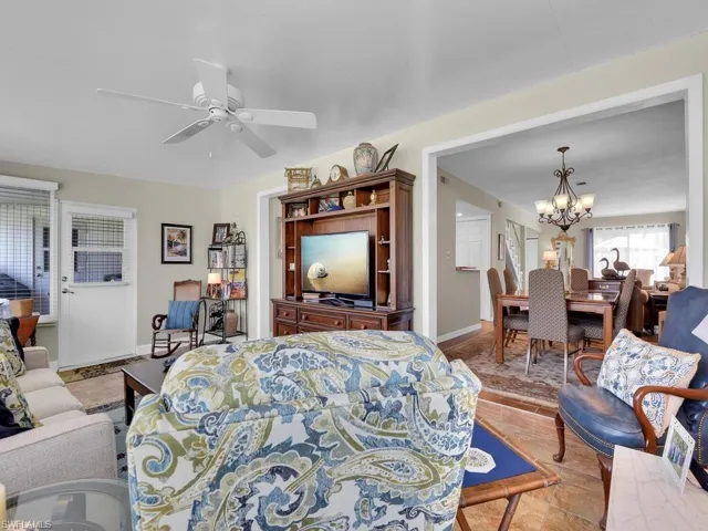 Living area featuring a chandelier, a ceiling fan, and baseboards