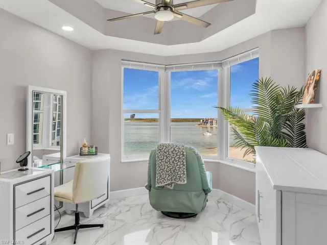 Office space with ceiling fan, a healthy amount of sunlight, and a water view
