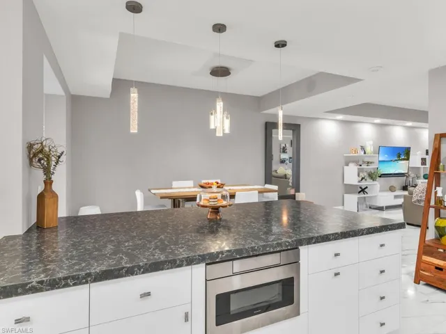 Kitchen featuring dark stone countertops, decorative light fixtures, and white cabinets