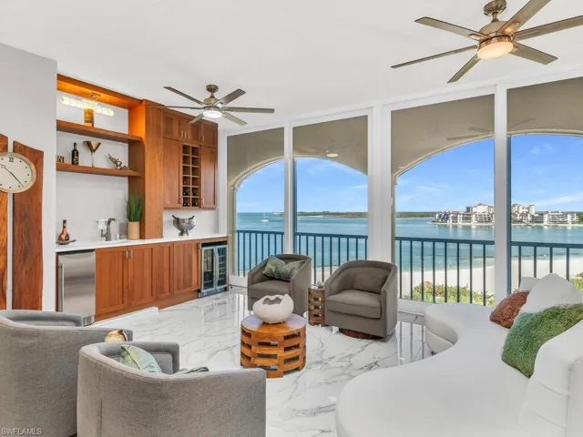 Living room featuring a water view, sink, ceiling fan, built in features, and wine cooler