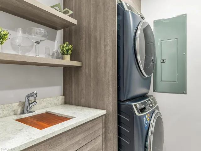 Laundry area with stacked washer / dryer, electric panel, and sink
