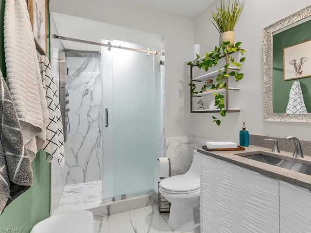 Bathroom with toilet, vanity, and an enclosed shower