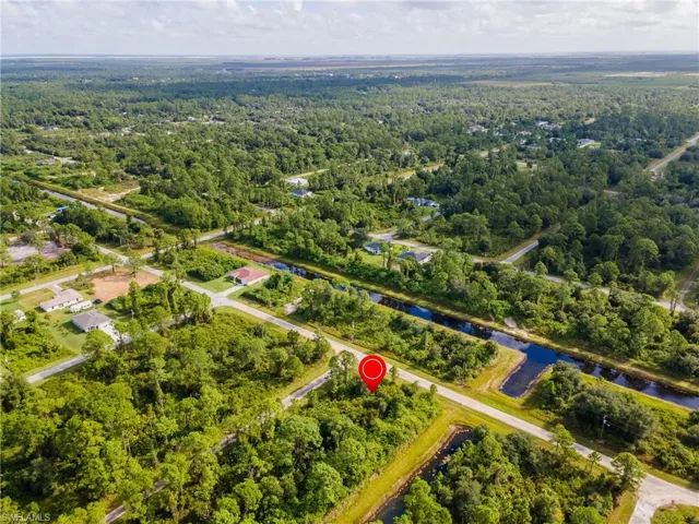 Aerial view of property and surrounding area with a heavily wooded area and a nearby body of water